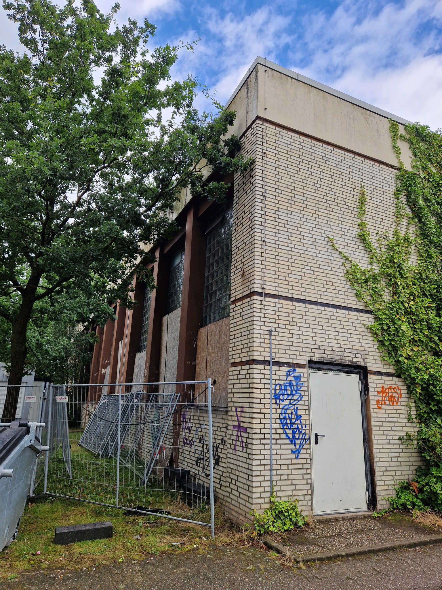 Gebäudeseite mit Graffiti und provisorischer Absperrung.